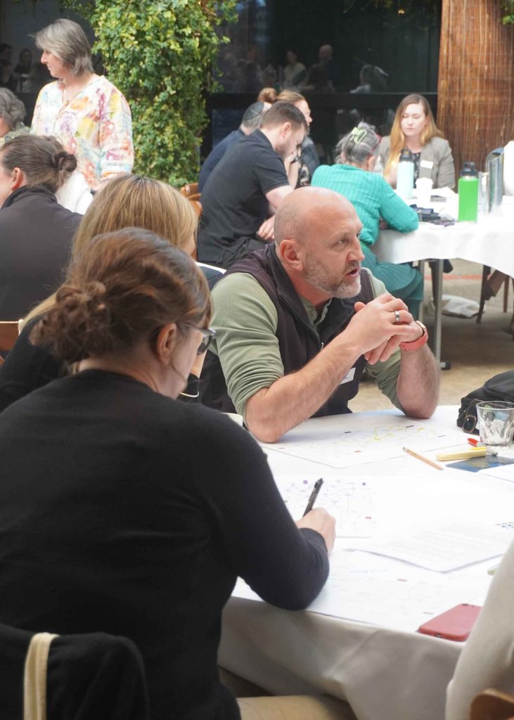 A team of people sitting around a table in discussion with notebooks and pens in front of them
